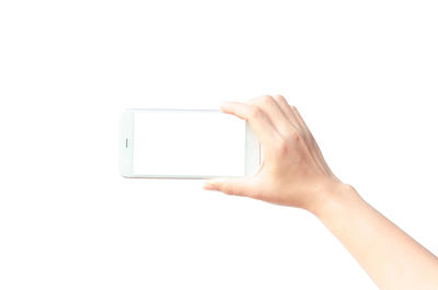 Cropped hand of person holding smart phone with blank screen against white background