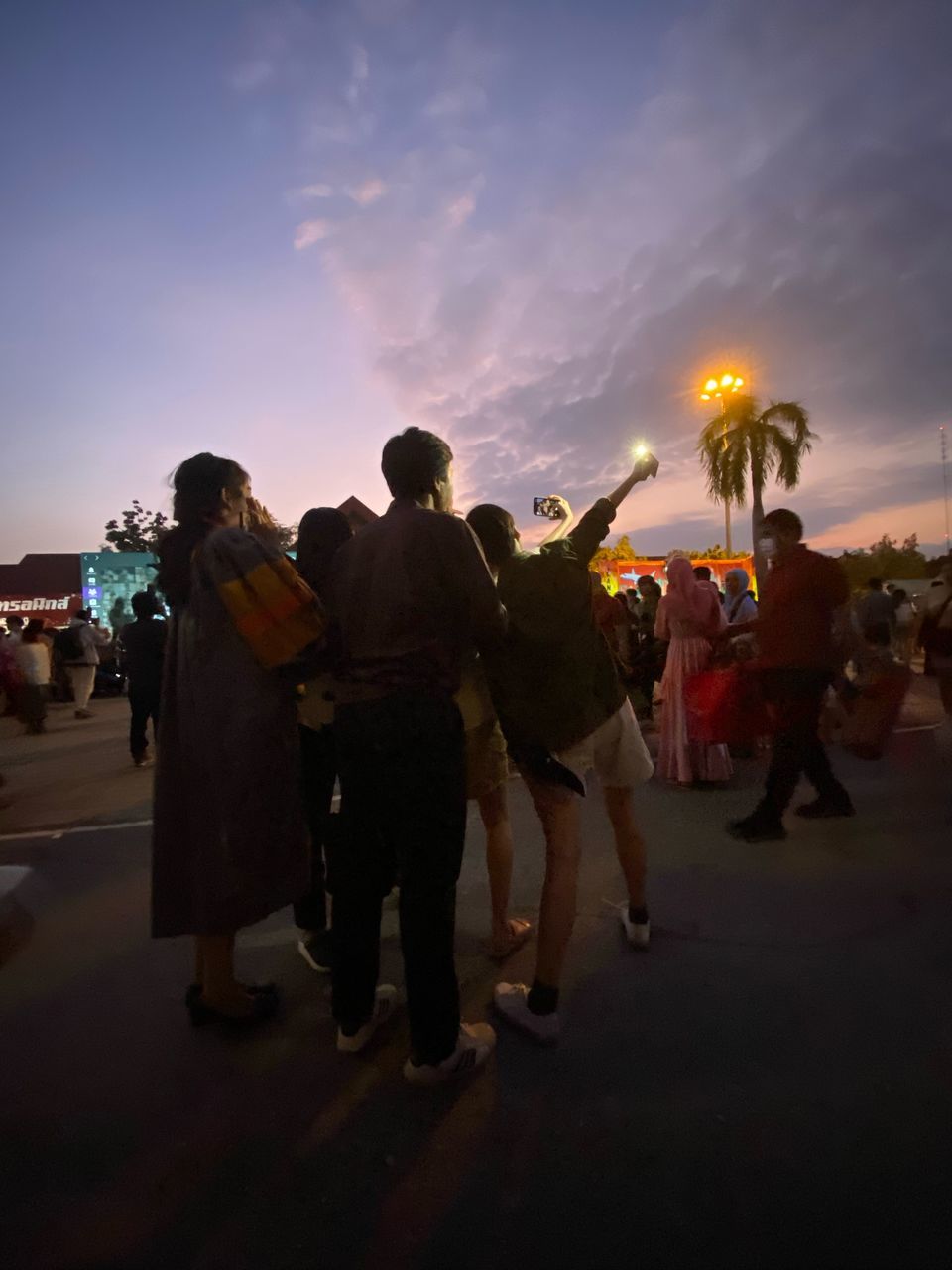 GROUP OF PEOPLE STANDING ON STREET DURING SUNSET