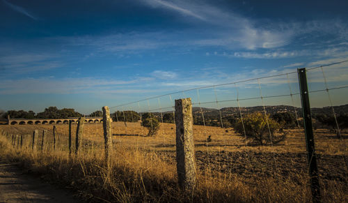 Wooden posts on field against sky