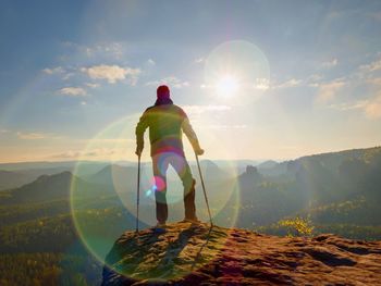 Rear view of man standing on mountain against sky during sunset