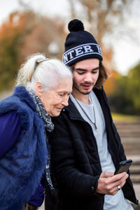 Grandson showing mobile phone to grandmother in park