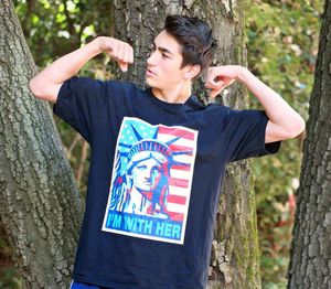 Full length of teenage boy standing by tree trunk in forest