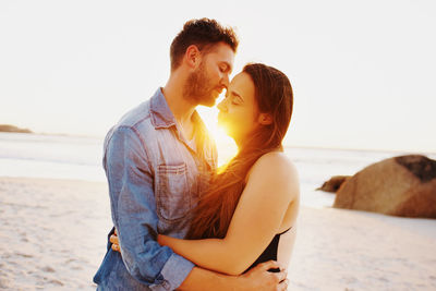 Young couple on beach against sky