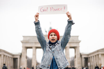 Portrait of young woman standing against wall