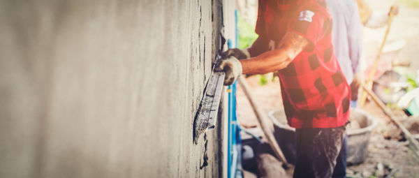 Midsection of man plastering wall