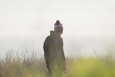 Rear view of woman standing on grassy field