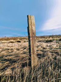 Close-up of wooden post on field against sky