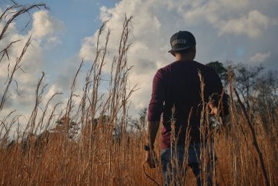 Rear view of man standing on field against sky