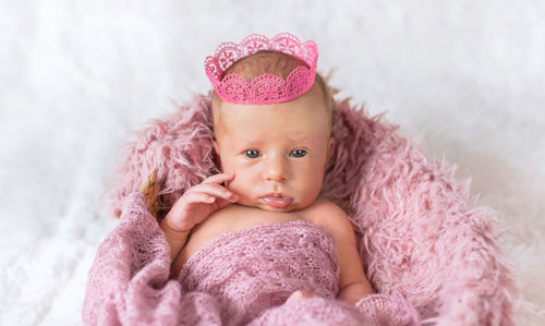 Portrait of cute baby girl lying on bed