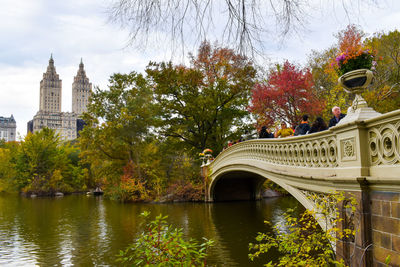 Bridge over river amidst trees against sky