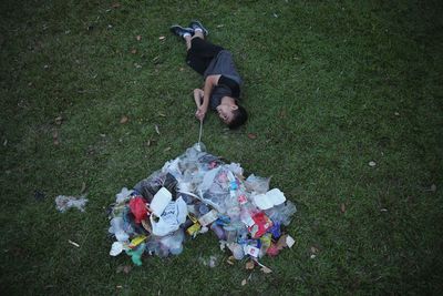 High angle view of man lying down by garbage on field