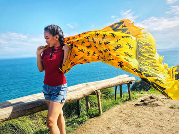 Full length of woman standing at beach against sky