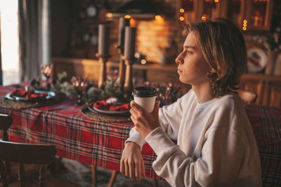 Portrait of candid authentic smiling handsome boy teenager using mobile phone at xmas home interior