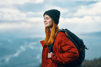 Young woman wearing hat standing against sky