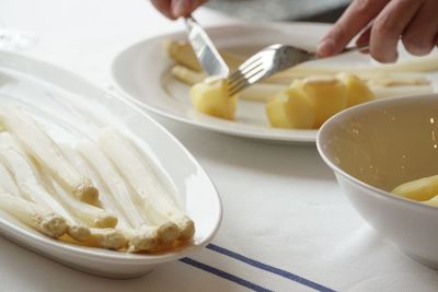 White asparagus by cropped hands having food on table