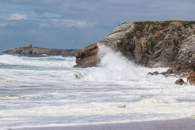 Rock formation on beach against sky