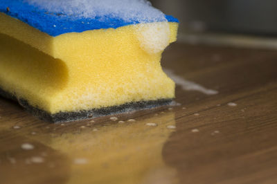 Close-up of cleaning sponge on wet wooden table