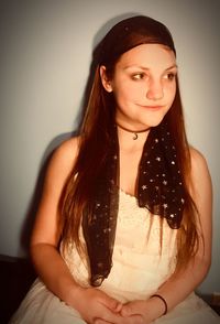 Portrait of beautiful young woman standing against wall