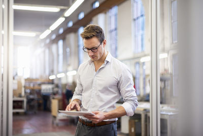 Young businessman in factory using tablet