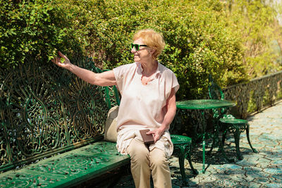 Mature beautiful woman traveler, sits on the bench of the park