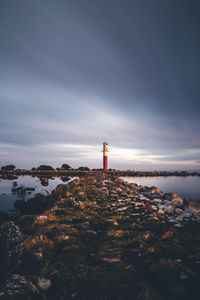 Lighthouse amidst buildings and sea against sky