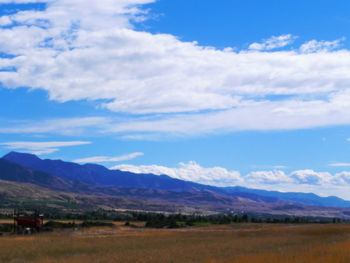 Scenic view of field and mountains against blue sky