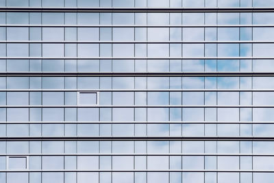 Glass facade of office buildings where the windows reflect the cloudy sky and create a perfect grid