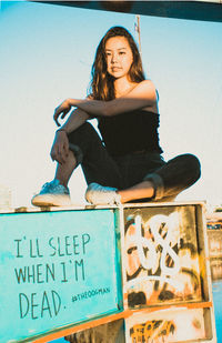 Low angle view of young woman standing against sky