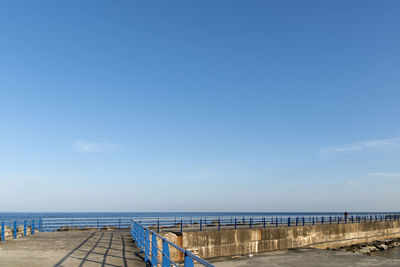 Pier over sea against blue sky