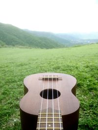 Close-up of guitar on field against sky