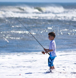 Boy fishing in sea on sunny day