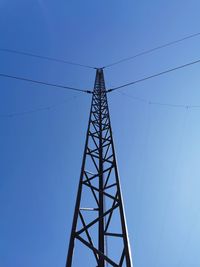 Low angle view of electricity pylon against clear blue sky