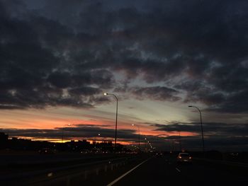 Cars on road against cloudy sky