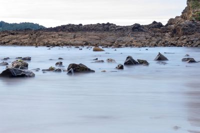 View of rocks in sea against sky