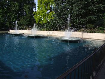 Water fountain in swimming pool by lake