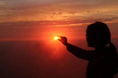 Silhouette of man using mobile phone against sunset sky