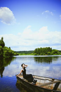 Man sitting on lake against sky