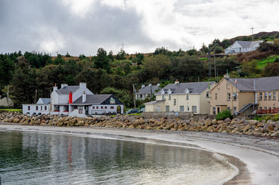 Houses by river and buildings against sky