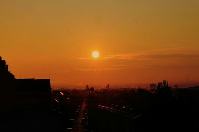 Silhouette of buildings against cloudy sky during sunset