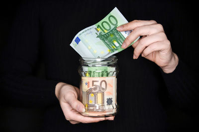 Close-up of hand holding paper against black background