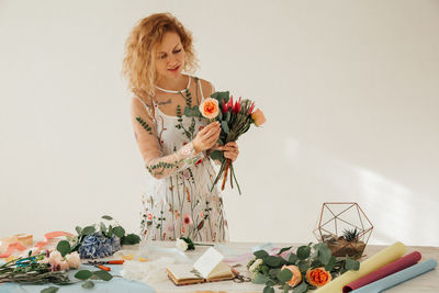 Woman holding flowers on table against white background