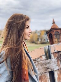 Beautiful young woman standing against sky