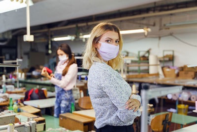 Woman wearing mask while working in factory