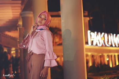 Portrait of beautiful young woman standing at night