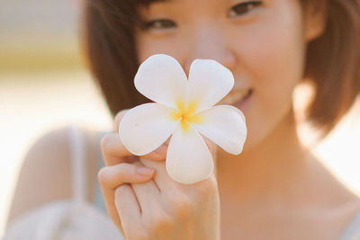 Close-up portrait of a woman holding red flower