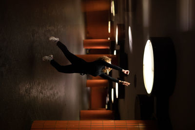 Upside down image of woman jumping in illuminated garage