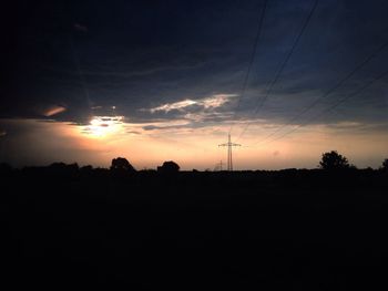 Silhouette of electricity pylon at sunset