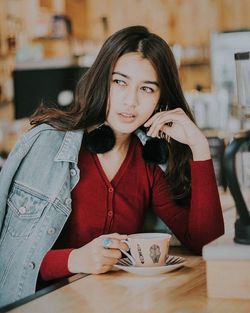 Portrait of young woman holding coffee cup on table