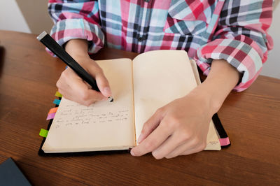 Midsection of woman reading book on table