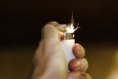 Close-up of hand holding lit candle